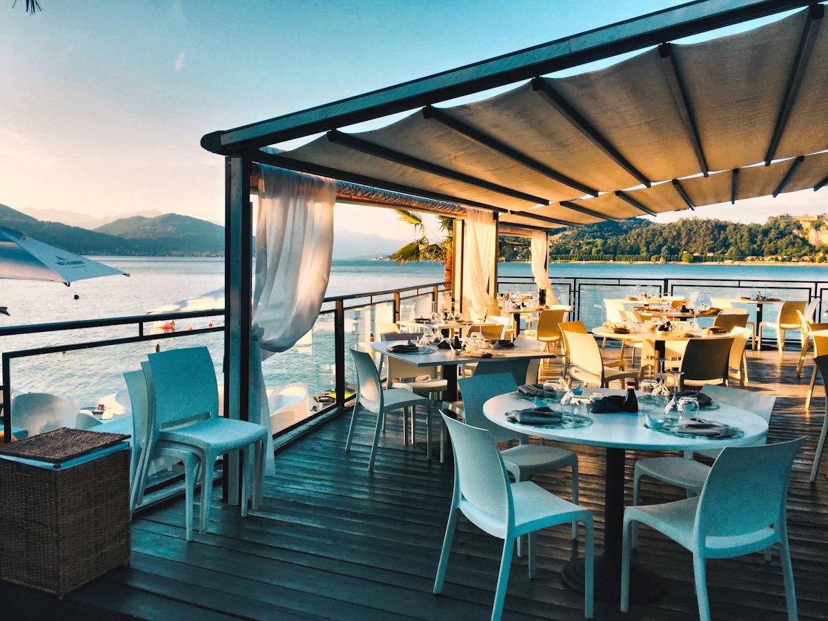A seaside restaurant terrace with set tables at sunset