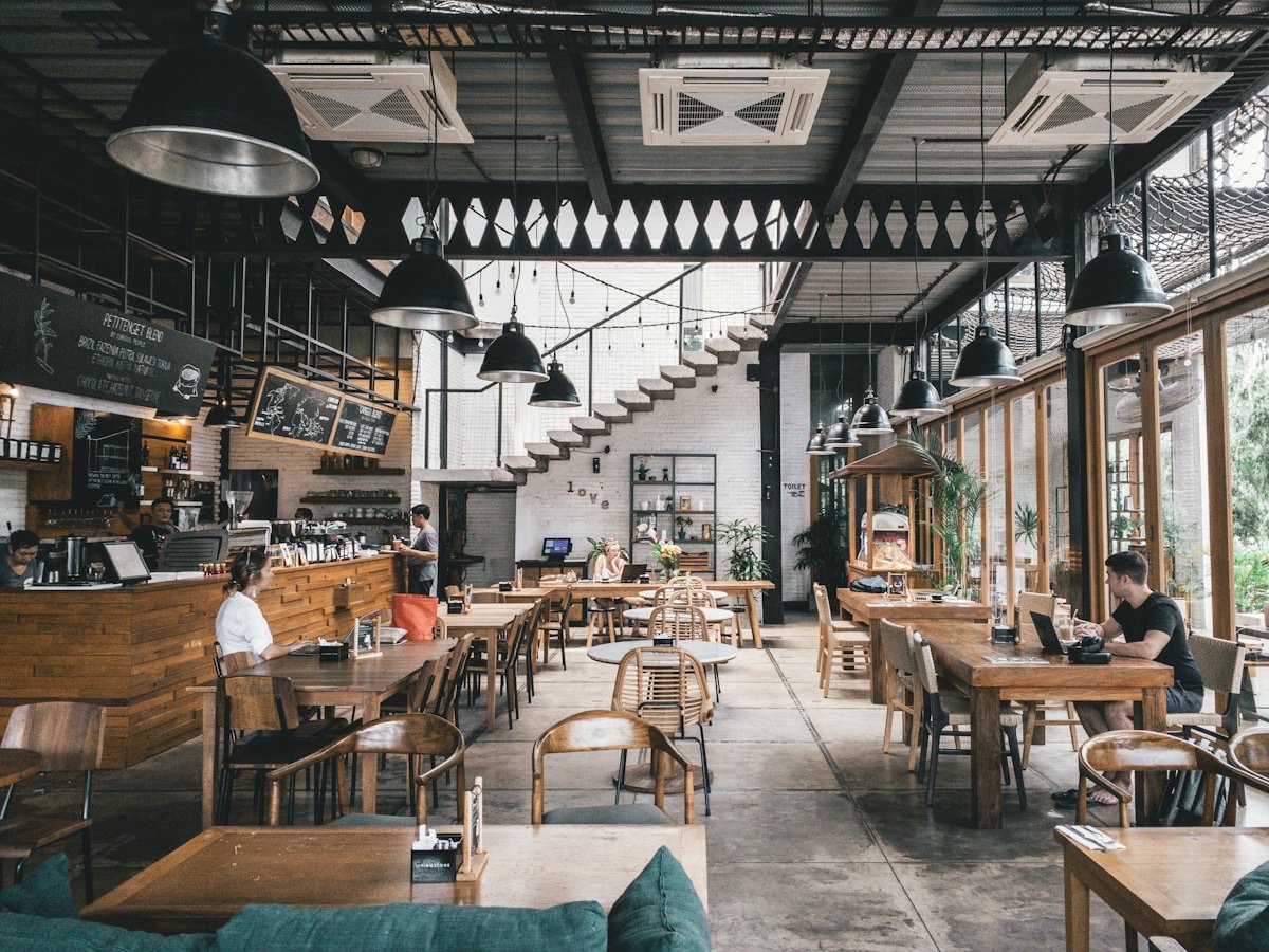 A busy, modern restaurant dining room with wooden tables and warm pendant lights